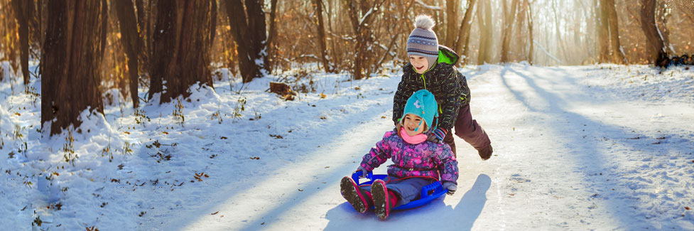 two children riding saucer on snow, California